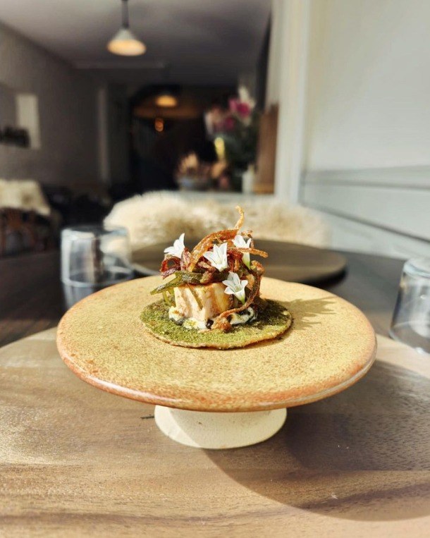 A plated course on a ceramic pedestal in the dining room
