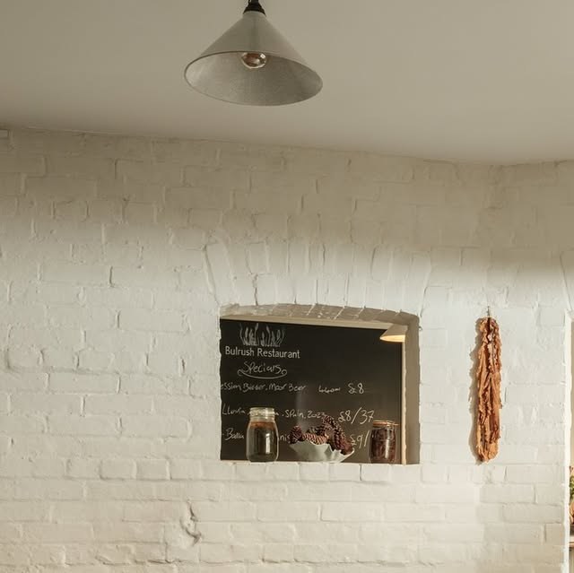The white-brick dining room with its blackboard and dried reeds